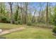 Grassy backyard bordered with mature trees; hexagonal pavers lead to a white-brick home at 2694 Benjamin E Mays Sw Dr, Atlanta, GA 30311