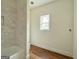 Bright bathroom featuring tiled tub/shower combination, window, and wood-look flooring at 4585 Parkwood Rd, Social Circle, GA 30025