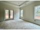 Bright primary bedroom featuring French doors and large windows overlooking the yard at 4585 Parkwood Rd, Social Circle, GA 30025