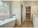 Bright bathroom featuring a soaking tub, modern fixtures, and a window with a view of nature at 4601 Parkwood Rd, Social Circle, GA 30025