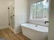 Clean bathroom with a walk-in shower and soaker tub, surrounded by neutral tile and bright windows at 4601 Parkwood Rd, Social Circle, GA 30025