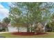 Two-story home boasts stone accents, neutral siding, well-manicured lawn and three mature trees at 100 Hugh Dr, Covington, GA 30016