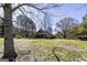 Wide shot of the house, with a long, grassy front yard, mature trees, and a storage building at 689 Hardin Rd, Temple, GA 30179