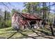 Rustic red shed with a weathered roof and open storage space, set in a grassy yard at 689 Hardin Rd, Temple, GA 30179