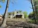 View of the rear exterior of a two story home with a large deck surrounded by lush trees and landscaping at 2481 Weatherstone Cir, Conyers, GA 30094