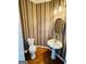 Classic powder room featuring pedestal sink, oval mirror, and wooden floors at 2481 Weatherstone Cir, Conyers, GA 30094