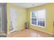 Sunny empty room showcasing hardwood floors, a bright yellow accent wall, and natural light at 105 Lantana Dr, Locust Grove, GA 30248