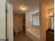 Bright bathroom features a tub with a window, neutral tiling, and a vanity with dark countertops at 191 Tumlin Creek Rd # 1, Roopville, GA 30170