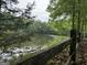Scenic view of the lake surrounded by lush greenery and a weathered wooden fence at 191 Tumlin Creek Rd # 1, Roopville, GA 30170