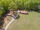 Wide aerial shot showcasing a red-roofed home, storage shed, and a sprawling lawn with mature trees at 361 Cecil Hunter Rd, Moreland, GA 30259