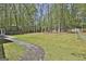 Spacious backyard featuring green grass, mature trees, a wood fence, and a brick walkway at 214 Windgate Ct, Peachtree City, GA 30269