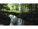 Scenic backyard view featuring a creek flowing near a charming home surrounded by lush greenery and trees at 2316 Emerald Dr, Jonesboro, GA 30236
