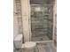 Bathroom featuring a stand-up shower, toilet, storage cabinet, and elegant blue-grey tile at 2316 Emerald Dr, Jonesboro, GA 30236