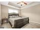 The main bedroom features a tray ceiling, ceiling fan, neutral colors and a large bed at 229 Primstone Way, Mcdonough, GA 30253