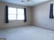 This bedroom features neutral carpet, basic lighting and a window with dark curtains at 30 Hickory Dr, Stockbridge, GA 30281