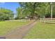 Long driveway leading to a charming home with white fencing, garage, and mature trees surrounding the property at 115 Ebenezer Church Rd, Fayetteville, GA 30215