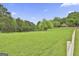Picturesque view of the expansive green field surrounded by trees, showcasing the property's natural beauty at 115 Ebenezer Church Rd, Fayetteville, GA 30215
