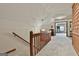 Upstairs hallway with neutral carpet, wood railing, and views of additional living spaces at 115 Ebenezer Church Rd, Fayetteville, GA 30215