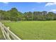 Expansive green pasture with white fencing and mature trees, offering a serene and private environment at 115 Ebenezer Church Rd, Fayetteville, GA 30215