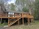 Backyard view featuring a raised deck with wooden stairs, brick house, and partial bamboo at 130 Sandy Dr, Stockbridge, GA 30281