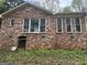 Brick home exterior with multiple windows, partial basement door, and some landscaping at 130 Sandy Dr, Stockbridge, GA 30281