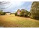 Brick home with landscaped yard and mature trees under cloudy skies, with additional home in the background at 118 Jasmine Way, Villa Rica, GA 30180