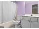 Bathroom featuring light purple walls, a shower-tub, toilet, and white cabinets at 2515 Harbins Mill Dr, Dacula, GA 30019