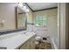 Classic bathroom featuring a window, decorative mirror, and neutral finishes at 242 Hickory Rd, Fayetteville, GA 30214