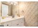 Classic bathroom with decorative wallpaper, a white vanity with ample storage, and elegant fixtures at 110 Kylemore Pass, Tyrone, GA 30290