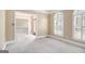 Bright living room featuring a large arched window, neutral carpet, and an open entryway to other living spaces at 110 Kylemore Pass, Tyrone, GA 30290