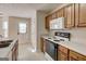 Galley kitchen featuring wood cabinetry, light countertops, and appliances at 11419 South Grove Dr, Hampton, GA 30228