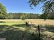 Fenced field offers ample space for recreation or agriculture, enhanced by its lush grass and private woodland at 183 Busbin Rd, Fayetteville, GA 30215