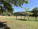 Vast back field with mature trees offers privacy and space, enhanced by a rustic fence, ideal for various outdoor pursuits at 183 Busbin Rd, Fayetteville, GA 30215