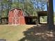 Red barn with white trim, featuring large doors and a sheltered overhang at 183 Busbin Rd, Fayetteville, GA 30215