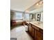 Bright bathroom featuring a large mirror, double vanity and sinks, white tub and tile flooring at 1600 Prospect Pl, Locust Grove, GA 30248