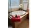 Bathroom featuring a white tub with tile surround, and bright window with flower decor at 1600 Prospect Pl, Locust Grove, GA 30248