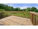 Wooden back deck with wood railings overlooking a lush green space and wood floorboards at 8103 Rhodes Way, Riverdale, GA 30274