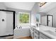 Bright bathroom featuring a soaking tub, glass-enclosed shower, and double vanity with black hardware at 8103 Rhodes Way, Riverdale, GA 30274