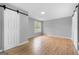 Spacious bedroom with a large window and modern barn-style sliding doors and wood-look flooring at 8103 Rhodes Way, Riverdale, GA 30274