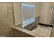 Modern bathroom features a soaking tub with marble surround and bright natural light from the window at 906 Winall Down Ne Rd, Atlanta, GA 30319