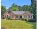 Charming brick home featuring a well-manicured lawn and mature trees on a sunny day at 75 The Farm Rd, Mcdonough, GA 30252