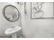 Bathroom featuring a pedestal sink, round mirror, and modern light fixture at 924 Bryson Lake Cir, Douglasville, GA 30134