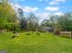 Beautiful backyard featuring a lush green lawn, a brick fire pit, and bordered by mature trees at 100 Little Creek Dr, Sharpsburg, GA 30277