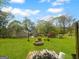 Expansive backyard with lush green lawn, brick fire pit, patio, and bordered by mature trees at 100 Little Creek Dr, Sharpsburg, GA 30277