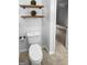 The updated powder room features wood shelves, a toilet, and neutral flooring at 100 Little Creek Dr, Sharpsburg, GA 30277