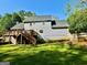 Back of the home featuring a wooden deck, lush green lawn, and mature trees at 149 Wimberly Way, Powder Springs, GA 30127
