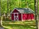 Backyard storage shed with white trim and a freshly painted red exterior at 149 Wimberly Way, Powder Springs, GA 30127