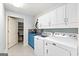 Well-lit laundry room with white cabinets, blue vanity, and modern patterned tile floor at 406 Kenley Ct, Mcdonough, GA 30253