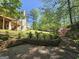 A beautifully landscaped backyard with mature trees and flowering bushes surrounding a patio area at 210 Sweetwater Dr, Fayetteville, GA 30214