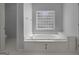 Elegant bathroom showcasing a jetted tub with decorative tile surround and block window at 210 Sweetwater Dr, Fayetteville, GA 30214